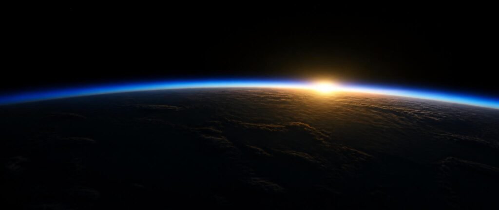 The thin blue atmosphere glowing along Earth's curved horizon seen from space at sunrise